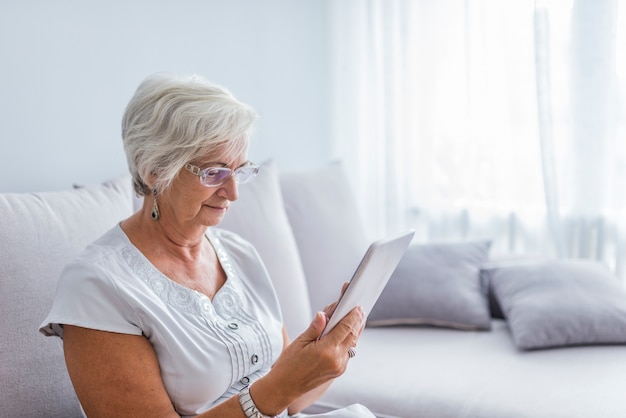 Senior woman reading a message, e-book or information on her tablet computer with a look o