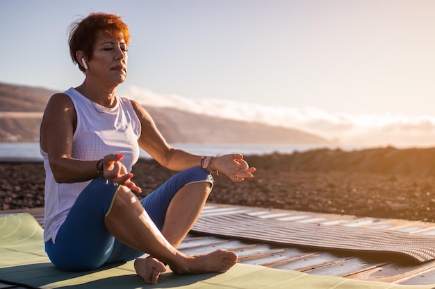 Senior woman relaxing and meditating by the sea