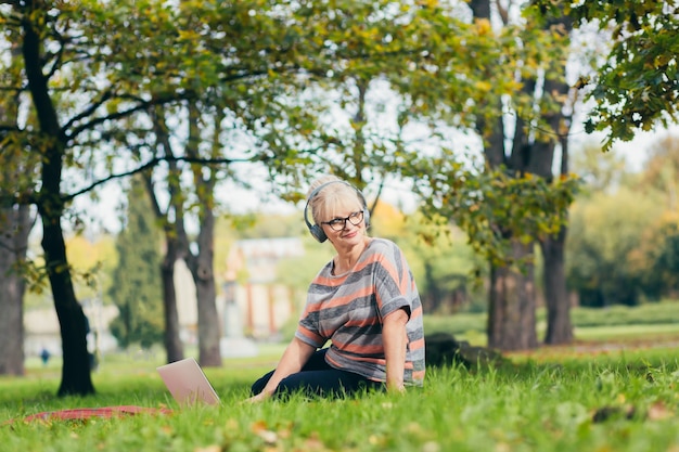 Senior donna rilassante nel parco con un computer portatile