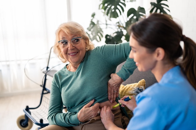 senior woman in retirement receiving her daily insulin injection therapy for diabetes treatment at home nurse injecting insulin with pen to elderly female patient providing home care services