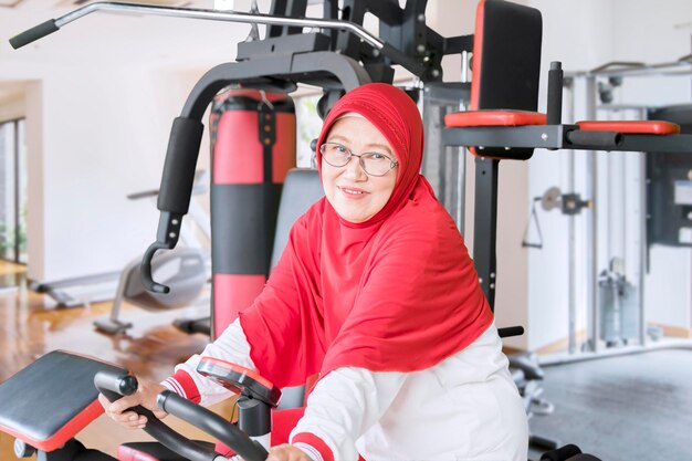 Senior woman riding exercise bike while smiling