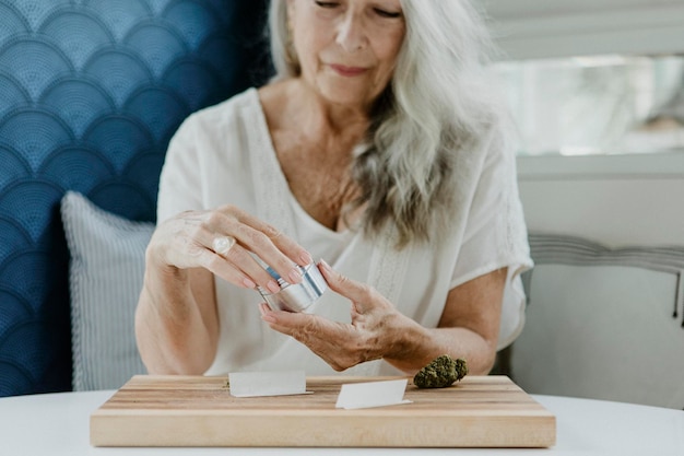 Photo senior woman rolling a joint