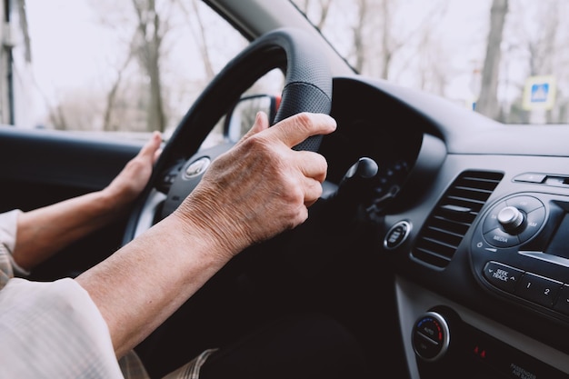 車を運転している年配の女性がハンドルを握る