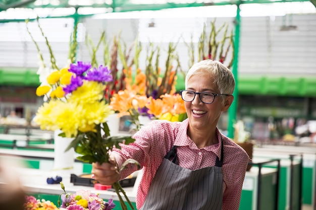 Senior woman sales flowers on local flower market