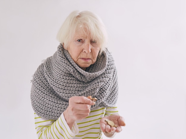 senior woman in scarf counting coins Poverty crisis oldness concept