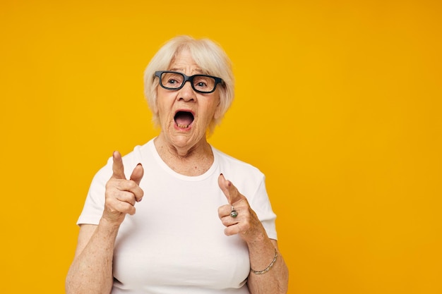 Senior woman screaming against yellow background