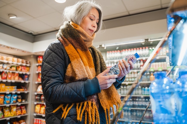 Senior woman selects a bottle of water in a market