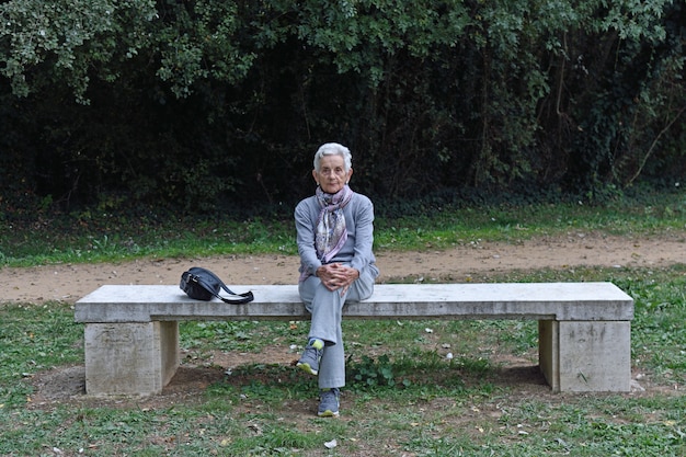 Senior woman sitting alone on a bench in a park