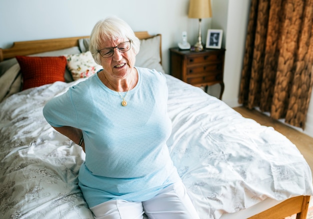 Senior woman sitting on the bed in pain