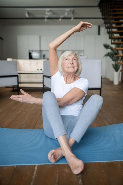 Senior woman sitting on a mat and doing exercises