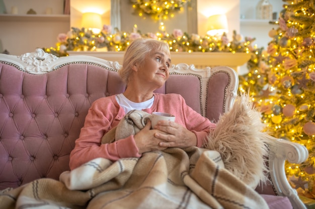 Senior woman sitting on a sofa and looking thoughtful