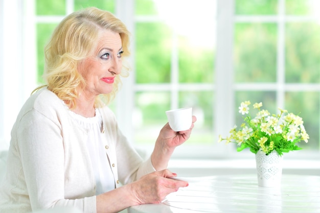 お茶とテーブルに座っている年配の女性