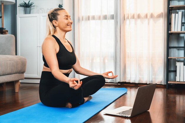 Senior woman in sportswear being doing yoga in meditation posture on exercising mat at home healthy senior pensioner lifestyle with peaceful mind and serenity clout