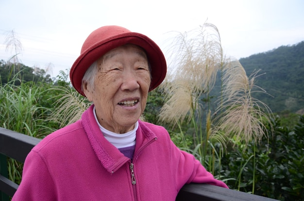 Foto donna anziana in piedi vicino alla recinzione contro la montagna