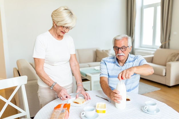 Senior woman standing and preparing breakfast Elderly couple feeling happy while having breakfast at home Mature woman smilling