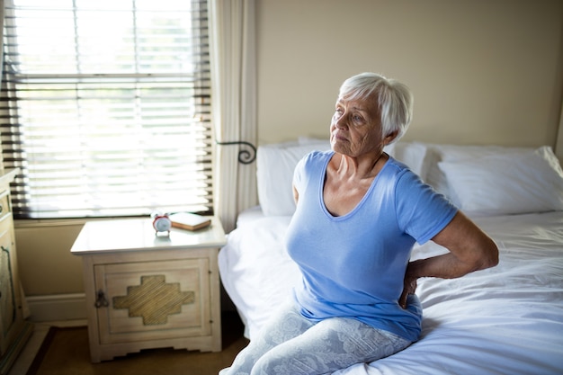 Senior donna che soffre di mal di schiena in camera da letto a casa