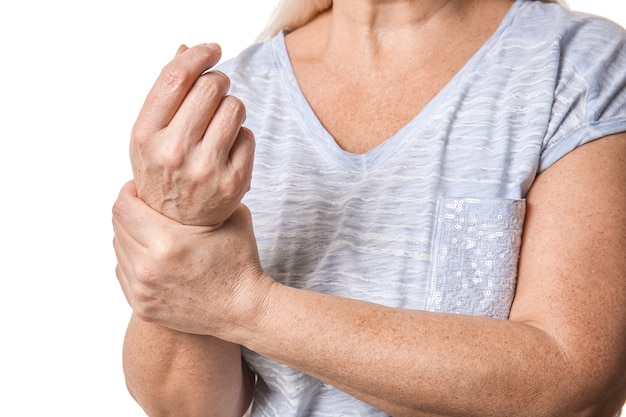 Photo senior woman suffering from parkinson syndrome on white wall, closeup