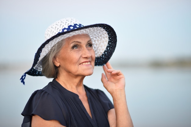 湖の近くの夏の年配の女性