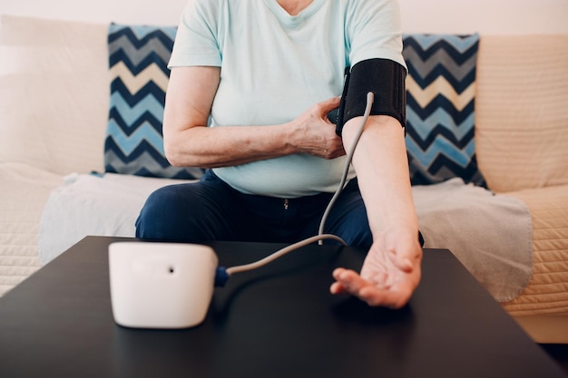 Senior woman taking measures blood pressure at home self care\
of elderly health