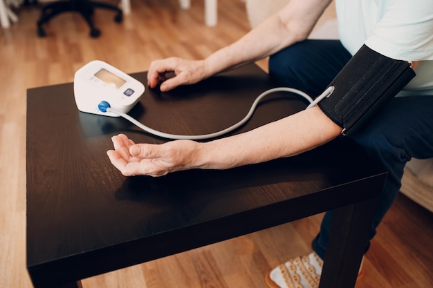 Senior woman taking measures blood pressure at home Self care of elderly health