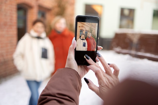 Photo senior woman taking a photo of her friends during their gathering