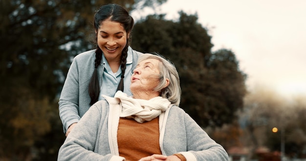 Фото Пожилая женщина разговаривает на открытом воздухе с опекуном медсестрой или медицинской службой для человека с инвалидностью и инвалидной коляской счастливое лицо и пожилая женщина в парке с уходом и поддержкой на пенсии