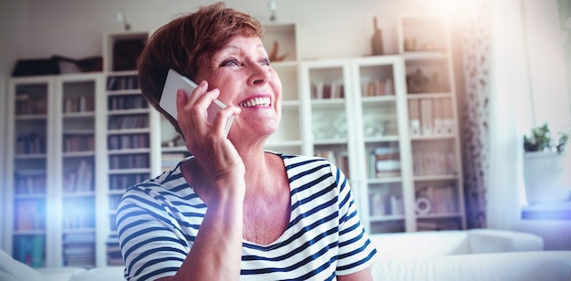 Foto donna anziana che parla al cellulare in soggiorno