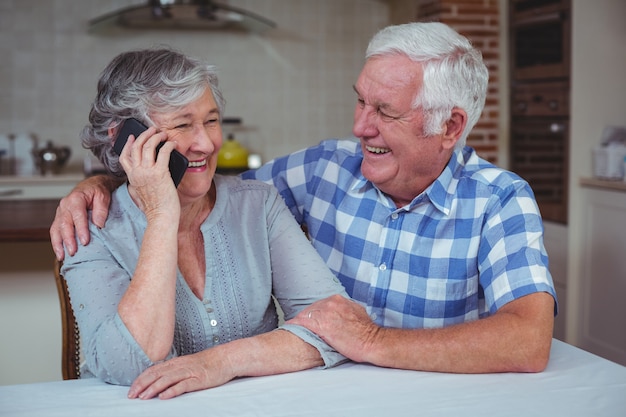 Senior woman talking on mobile phone while sitting with husband