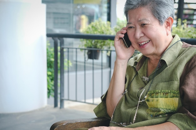 Photo senior woman talking on mobile while sitting on bench at park