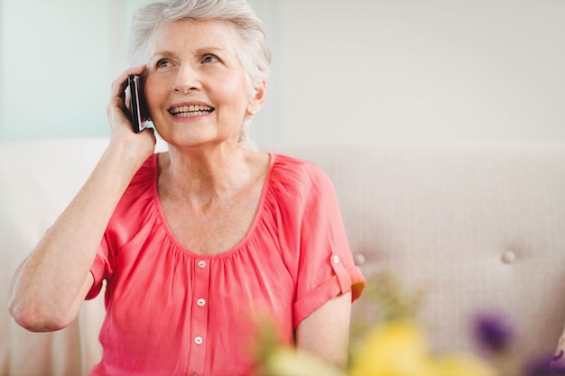 Senior woman talking on phone in living room