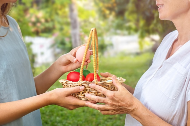 Senior donna e ragazza teenager che tiene cesto con uova di pasqua all'aperto