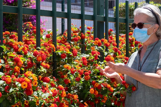 Foto donna anziana che tocca i fiori nel parco