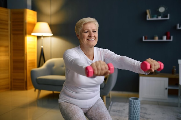 Senior woman training with dumbbell at home. Fitness training on quarantine. Body care on retirement