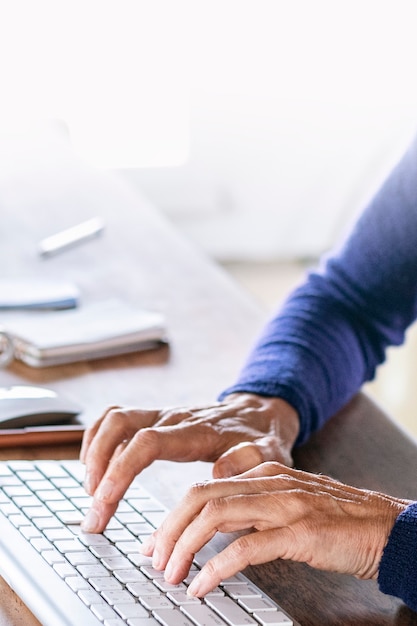 Donna anziana che digita sulla tastiera di un computer