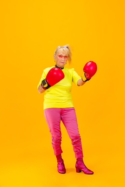 Senior woman in ultra trendy attire isolated on bright green background