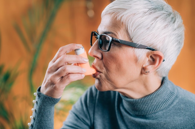 Photo senior woman using asthma inhaler with extension tube