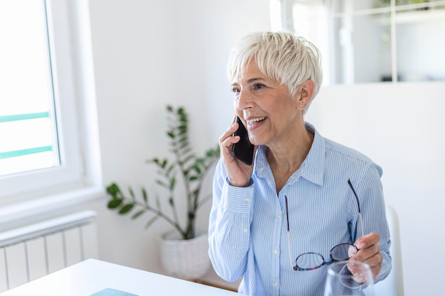 Senior woman using her phone. Happy woman relaxing at home, she is talking on her smartphone