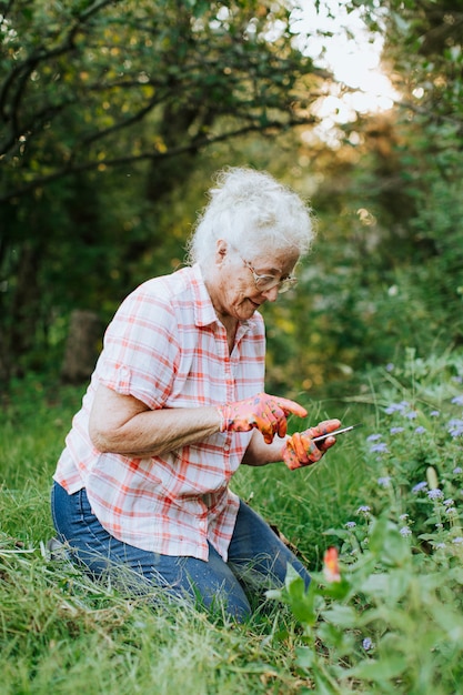 Senior woman using her phone while gardening