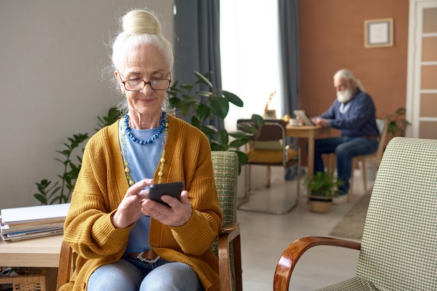 Senior woman using her smartphone at home