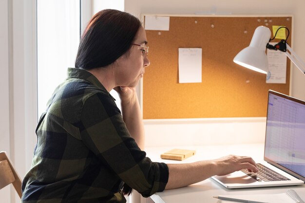 Senior woman using laptop in home office.