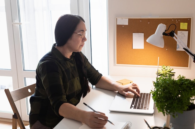 Senior woman using laptop in home office.