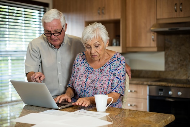 Senior donna utilizzando laptop in cucina a casa