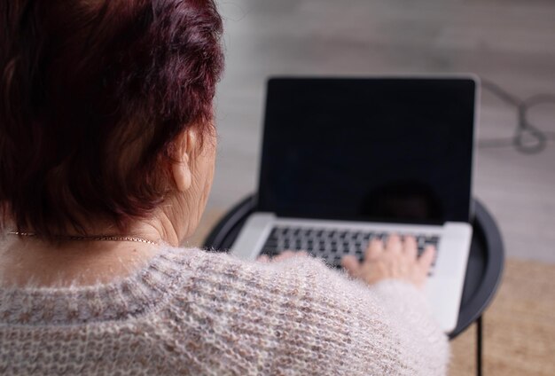 Senior woman using laptop on table at home