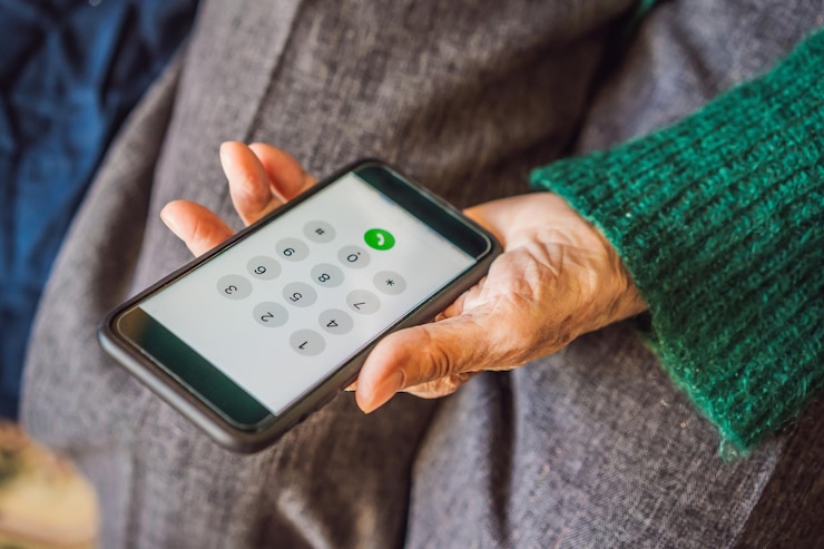 Photo senior woman using mobile phone while sitting on sofa