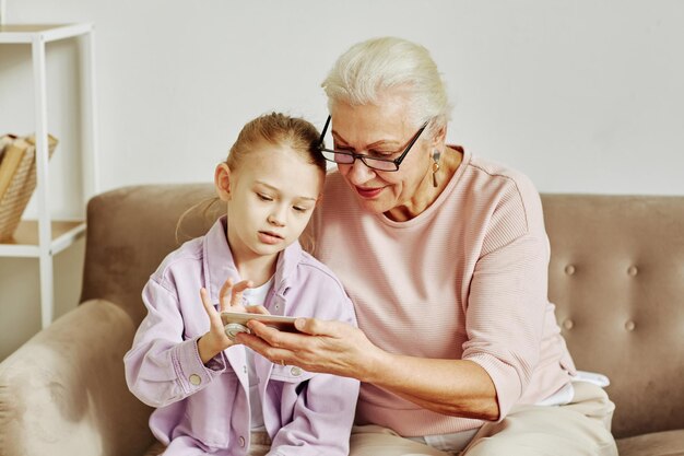 小さな女の子とスマートフォンを使用して年配の女性