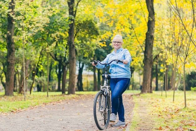 自転車で公園を歩く年配の女性