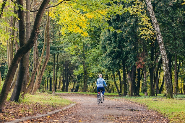 自転車で公園を歩く年配の女性