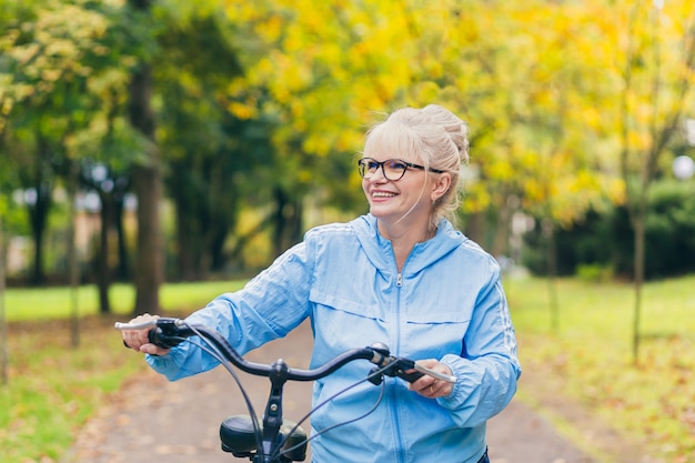 senior woman walking in the park with a bicycle