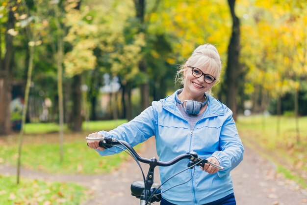 senior woman walking in the park with a bicycle