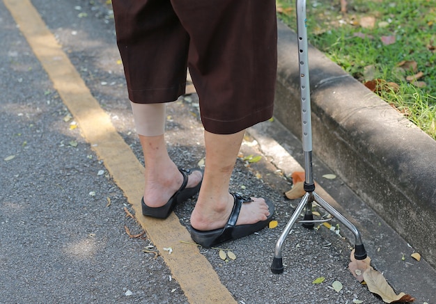 Senior woman walking with aluminium stick in the park